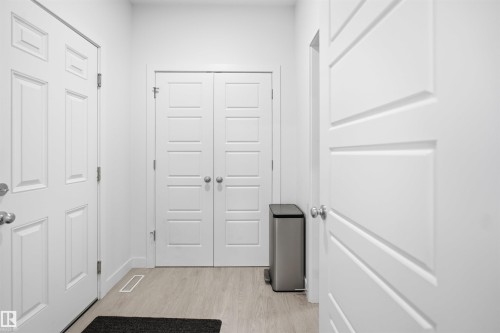 Bright entryway with light wood-finish flooring, featuring multiple paneled doors and modern hardware - 2508 193 Street, Edmonton, AB 