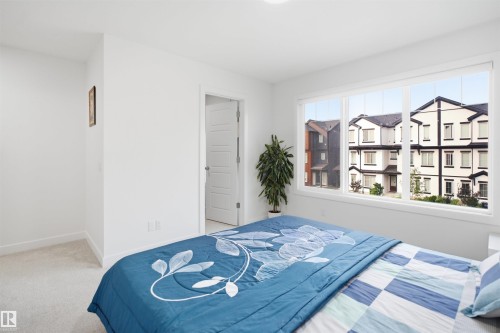Spacious room featuring broad windows with white trim, light-toned carpeting, and a white interior door with panel detailing - 2508 193 Street, Edmonton, AB 