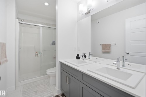 Modern bathroom featuring a dual vanity with rectangular undermount sinks, chrome faucets, and a full-width mirror - 2508 193 Street, Edmonton, AB 