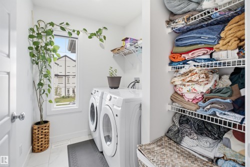 Dedicated laundry area featuring a window, built-in shelving, and a tiled floor - 2508 193 Street, Edmonton, AB 