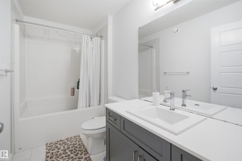 Contemporary bathroom featuring a dark grey vanity with a white countertop and an integrated rectangular sink - 2508 193 Street, Edmonton, AB 