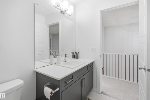 Bathroom featuring a vanity with a white countertop and undermount sink, a chrome faucet, and gray cabinetry with brushed nickel hardware - 2508 193 Street, Edmonton, AB 