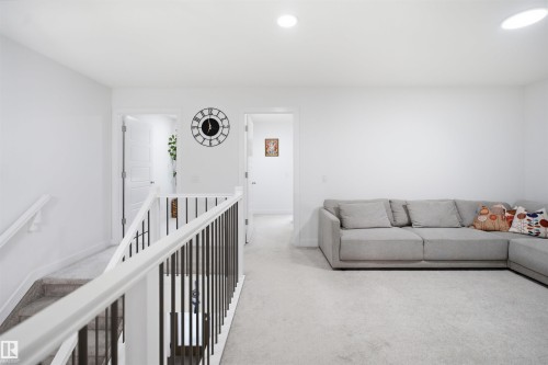 Second-story landing featuring white walls, recessed lighting, carpet flooring, and white banisters with dark metal balusters - 2508 193 Street, Edmonton, AB 