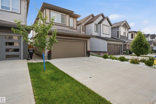 Contemporary facade featuring gray siding and trim, a dual-pane window, and an attached two-car garage with a brown door - 2508 193 Street, Edmonton, AB 