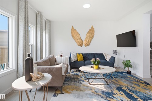 Living area featuring multiple large windows, light-toned walls, and wood-finish flooring - 2508 193 Street, Edmonton, AB 