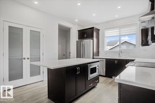 Modern kitchen featuring dark wood cabinetry, white countertops, and stainless steel appliances - 2852 Duke Crescent, Edmonton, AB 