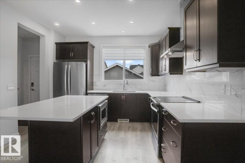 Modern kitchen featuring dark wood-finish cabinetry, light countertops, and a white tile backsplash - 2852 Duke Crescent, Edmonton, AB 