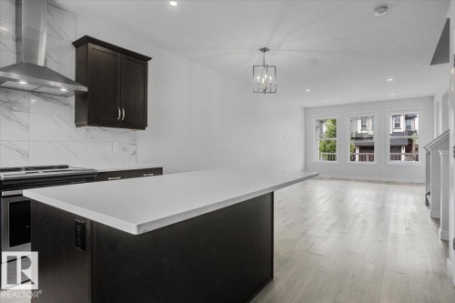 Modern kitchen featuring dark cabinetry, a white countertop island, and stainless steel appliances - 2852 Duke Crescent, Edmonton, AB 