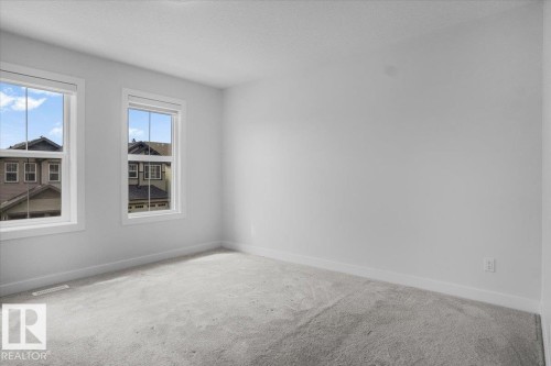 Bright room featuring two large windows with white trim, light gray carpet, and crisp white walls - 2852 Duke Crescent, Edmonton, AB 