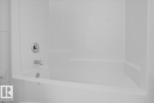 White tub and shower combination with chrome fixtures and integrated shelving - 2852 Duke Crescent, Edmonton, AB 