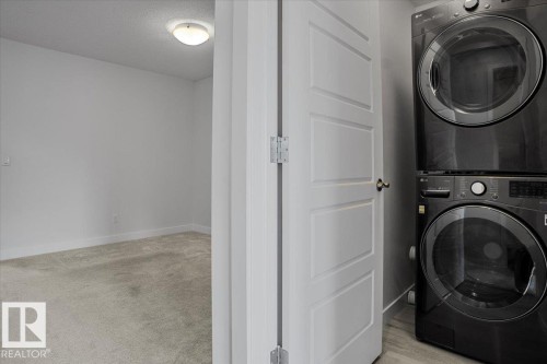Modern laundry area featuring a stacked washer and dryer unit - 2852 Duke Crescent, Edmonton, AB 