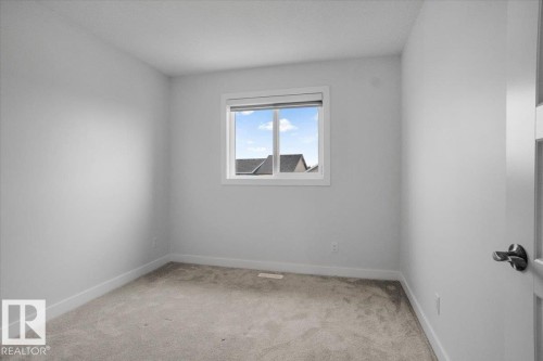 Interior room featuring light gray carpeting, white baseboards, and a white window frame - 2852 Duke Crescent, Edmonton, AB 