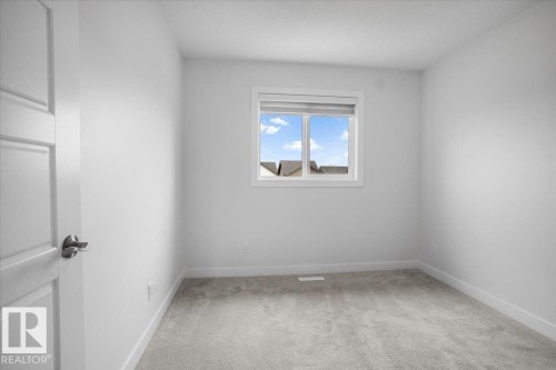Room featuring light gray carpet flooring, white walls, white trim, a single window with blinds, and a white interior door with a brushed nickel handle - 2852 Duke Crescent, Edmonton, AB 
