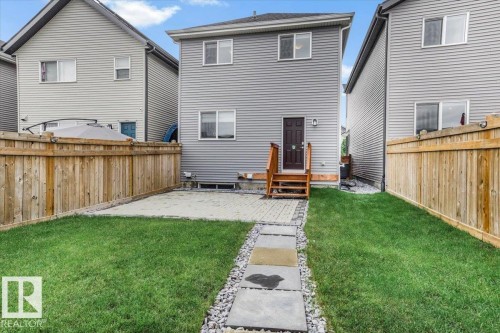 Rear exterior featuring grey horizontal siding, a wooden deck with stairs, and a dark brown door - 2852 Duke Crescent, Edmonton, AB 