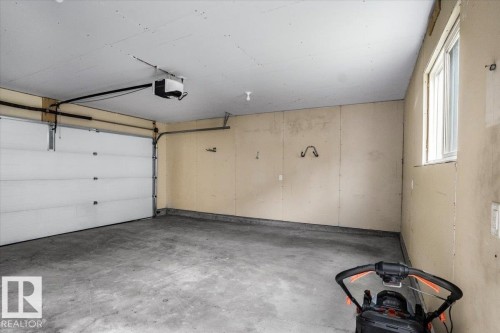 Spacious garage featuring a concrete floor, overhead lighting, and a window for natural light - 2852 Duke Crescent, Edmonton, AB 