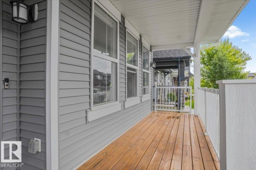 Front porch featuring wood-finish flooring, white railing, and grey siding - 2852 Duke Crescent, Edmonton, AB 
