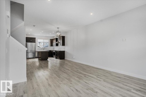 Open-concept living area featuring wood-finish flooring, recessed lighting, and a contemporary kitchen - 2852 Duke Crescent, Edmonton, AB 
