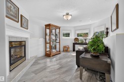 Living area featuring a tiled fireplace with a mantel, ceiling-mounted lighting, recessed lighting, and multiple windows - 