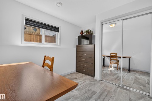 Bright interior room featuring a window with black blinds, light gray wood-look tile flooring, and a mirrored sliding closet door - 5006 53 Avenue, Cold Lake, AB 