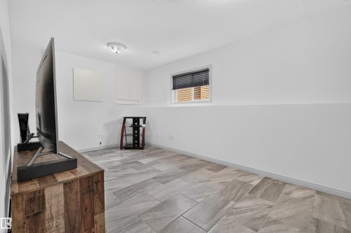 Spacious room featuring light gray tile flooring laid in a herringbone pattern, white painted walls, and built-in white cabinetry - 5006 53 Avenue, Cold Lake, AB 