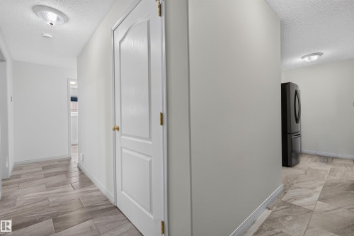 Hallway with wood-look tile flooring and white baseboards - 5006 53 Avenue, Cold Lake, AB 