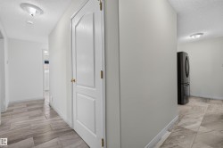 Hallway with wood-look tile flooring and white baseboards - 
