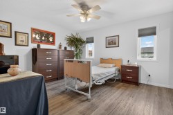 Spacious room featuring wood-finish flooring, white walls, and a ceiling fan with integrated lighting - 