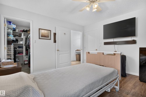 Bedroom featuring wood-finish flooring, a ceiling fan with integrated lighting, and a built-in closet with shelving - 5006 53 Avenue, Cold Lake, AB 