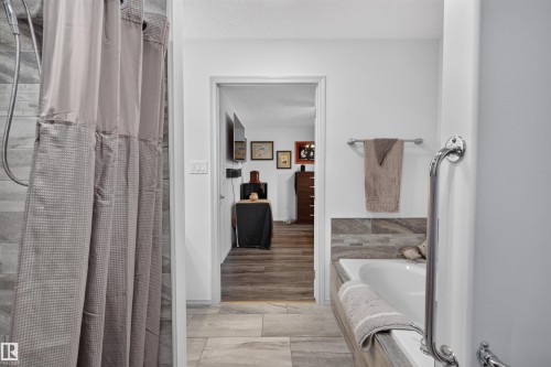Bathroom featuring a tiled shower surround, built-in bathtub, and chrome fixtures - 5006 53 Avenue, Cold Lake, AB 