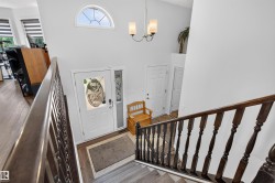 Foyer featuring a decorative glass front door with sidelight, vaulted ceiling, and an arched transom window - 