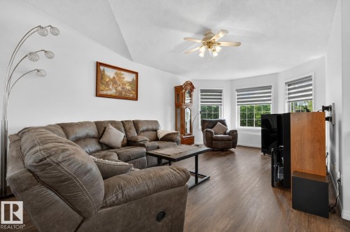Living area featuring wood-finish flooring, a ceiling fan, and a prominent bay window with three individual window units - 5006 53 Avenue, Cold Lake, AB 