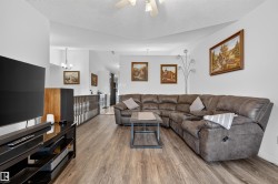Spacious living area featuring wood-finish flooring, vaulted ceiling, and an open concept layout - 