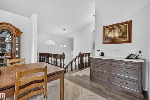 Open-concept interior featuring wood-finish flooring, a built-in console with a light-toned countertop, and a half-arch window - 5006 53 Avenue, Cold Lake, AB 