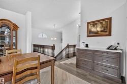Open-concept interior featuring wood-finish flooring, a built-in console with a light-toned countertop, and a half-arch window - 