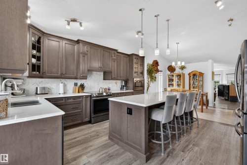 Modern kitchen featuring wood-finish flooring, white countertops, and a herringbone tile backsplash - 5006 53 Avenue, Cold Lake, AB 