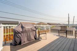 Spacious outdoor deck featuring composite decking, white railing, and a gas line connection - 