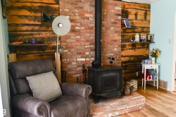 Brick fireplace with a black wood-burning stove and a brick hearth - 