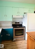 Kitchen featuring a stainless steel electric range, white subway tile backsplash, and light-colored countertops - 