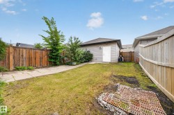 Expansive backyard featuring a detached accessory building, mature privacy fencing, concrete pathway, and established plantings - 