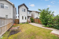 Rear exterior featuring light gray siding, dark trim, a walk-out basement, and a wooden deck with stairs to the backyard - 