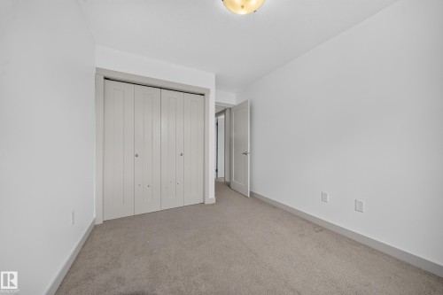 Room featuring neutral wall tones, gray carpeting, and a bi-fold closet with panel detailing - 227 Cy Becker Blvd, Edmonton, AB 