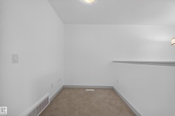 Carpeted room featuring white walls, gray baseboards, a ceiling-mounted light fixture, and a wall-mounted light fixture - 