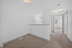 Carpeted hallway featuring white walls, gray baseboards, and white interior doors - 