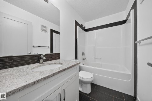 Bathroom featuring a white vanity with granite-finish countertop, integrated sink, and chrome faucet - 227 Cy Becker Blvd, Edmonton, AB 