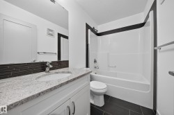 Bathroom featuring a white vanity with granite-finish countertop, integrated sink, and chrome faucet - 