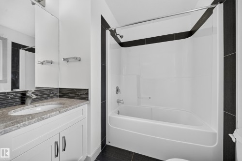 Bathroom featuring a white vanity with slab cabinet doors, granite countertop, and undermount sink - 227 Cy Becker Blvd, Edmonton, AB 