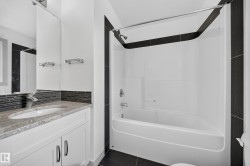 Bathroom featuring a white vanity with slab cabinet doors, granite countertop, and undermount sink - 