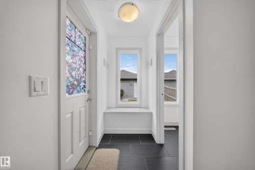 Entryway featuring a decorative glass door, black tile flooring, and a built-in window bench - 227 Cy Becker Blvd, Edmonton, AB 