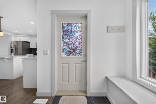 Entryway featuring a decorative stained-glass panel door, built-in window bench, and dark tile flooring - 227 Cy Becker Blvd, Edmonton, AB 