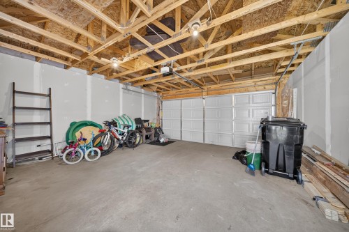 Spacious two-car garage with unfinished ceiling, concrete flooring, and an automatic garage door opener - 227 Cy Becker Blvd, Edmonton, AB 